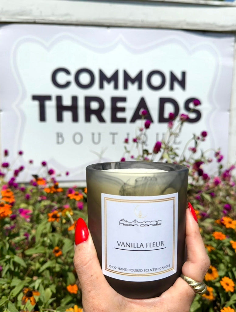 Picture of hand hold Autumn Moon Candle Vanilla Fleur Candle in from of Common Threads Boutique in Smryna Georgia