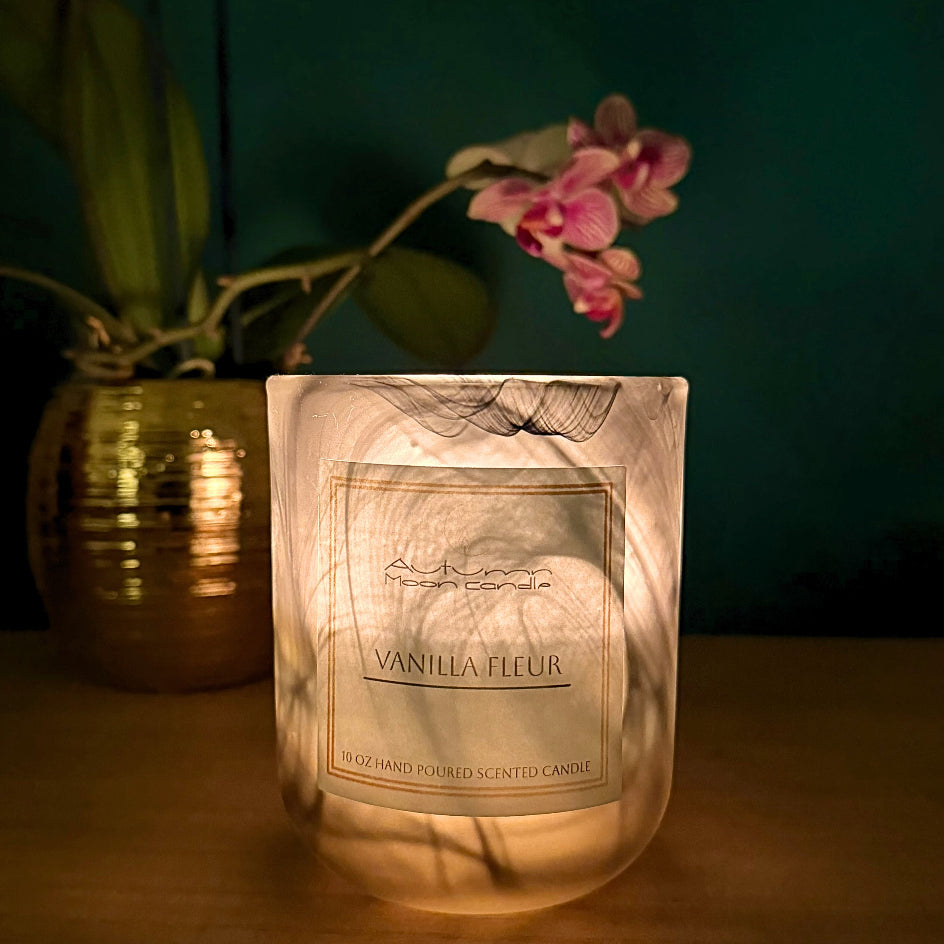 Luminous Autumn Moocandle labeled 'Vanilla Fleur' with a plant and pink flower in the background