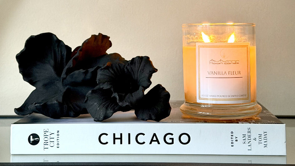 Autumn MoonCandle jar candle with black flowers and a book titled 'Chicago' on a white background