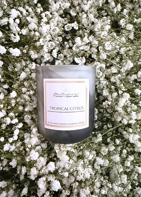 Autumn Moon Candle 10oz Tropical Citrus candle on a bed of flowers